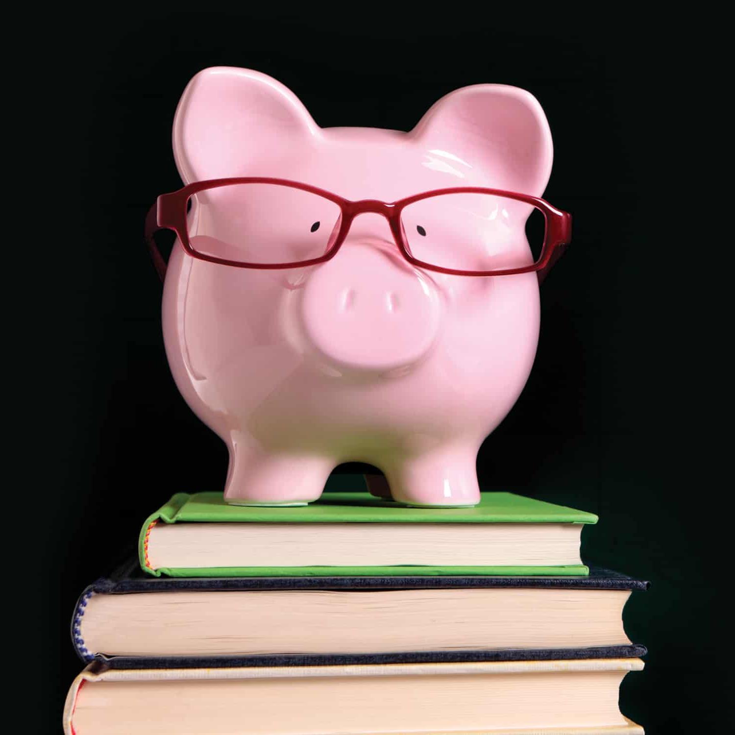 粉红色的小猪储蓄罐戴着红色的眼镜，上面放着一摞书